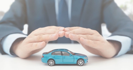 man holding hands over miniature car